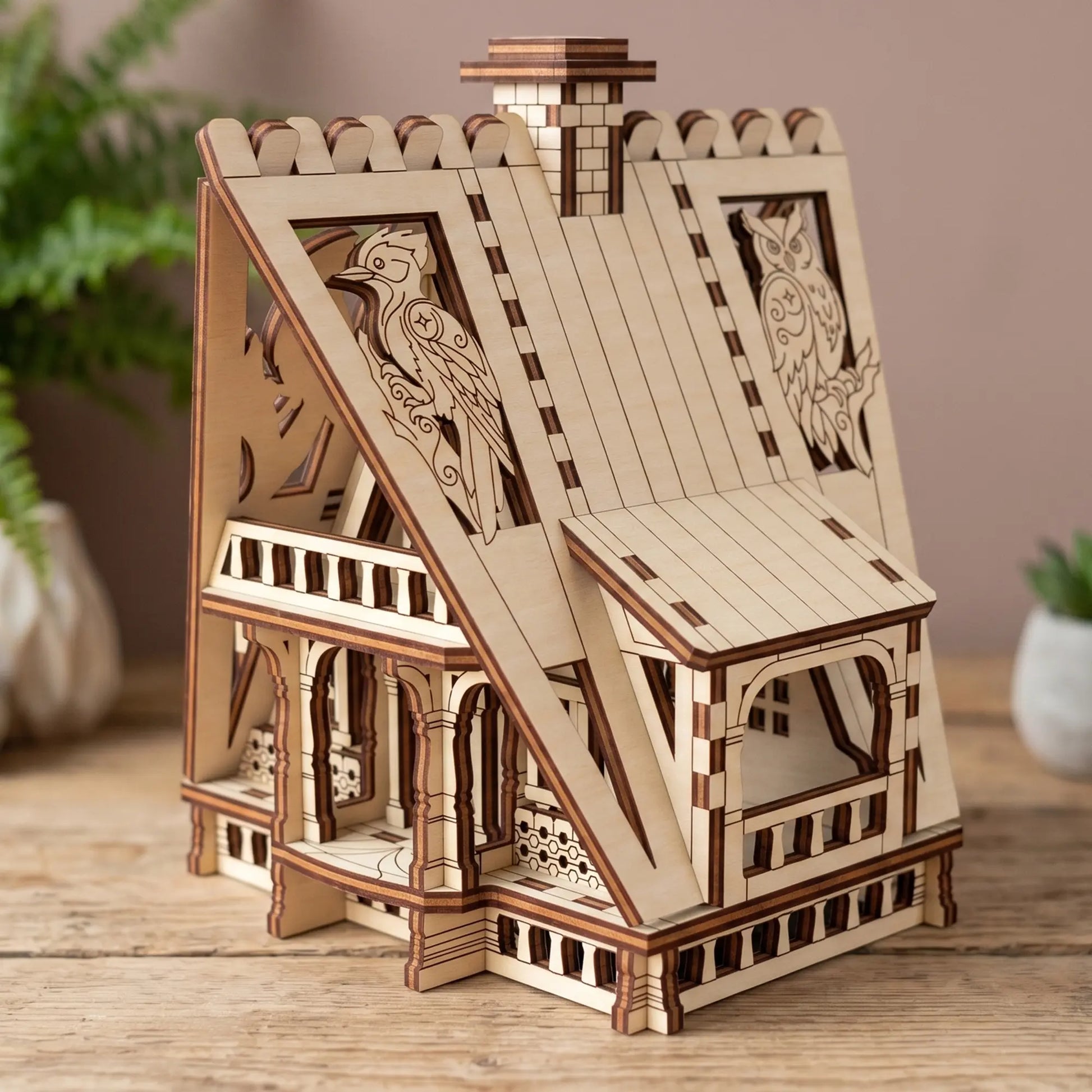 Side view of a miniature wooden fairy house with a balcony porch, constructed from two-tone laser cut plywood.