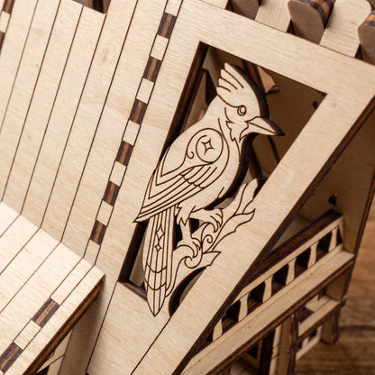 Macro shot of a detailed crested blue jay bird engraving on a miniature house panel made of laser cut plywood.