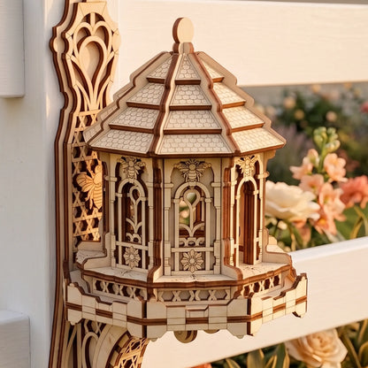 A laser-cut wooden fairy bee house with an intricate multi-tiered roof on a white fence