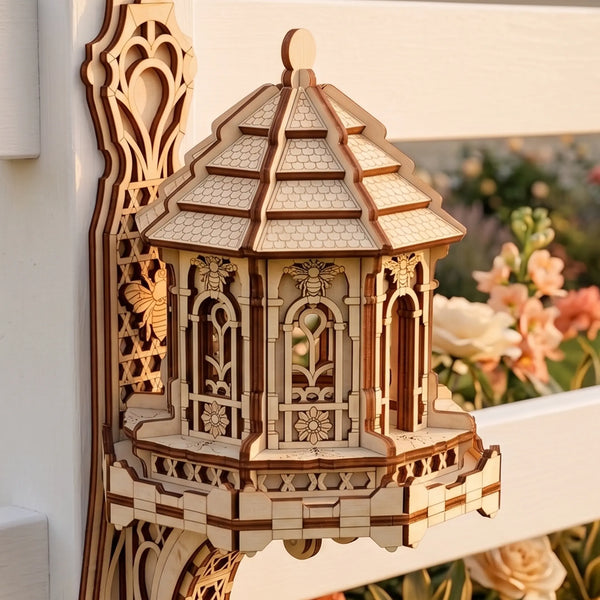 A laser-cut wooden fairy bee house with an intricate multi-tiered roof on a white fence