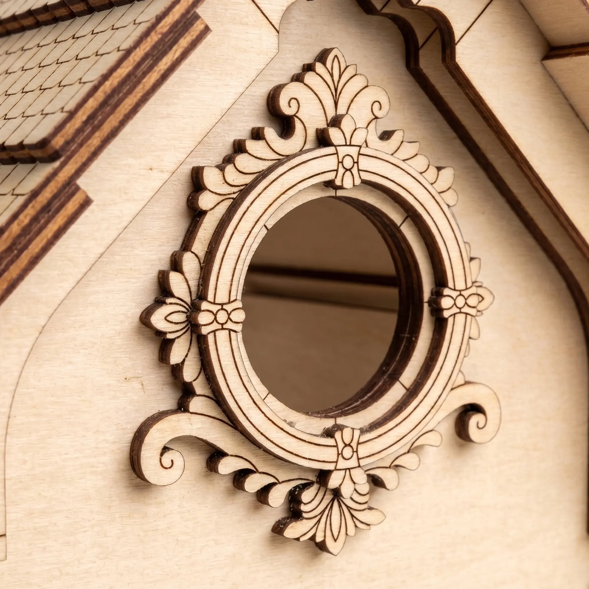 Close-up view of the decorative circular window trim and layered shingle roof of a laser cut plywood birdhouse.