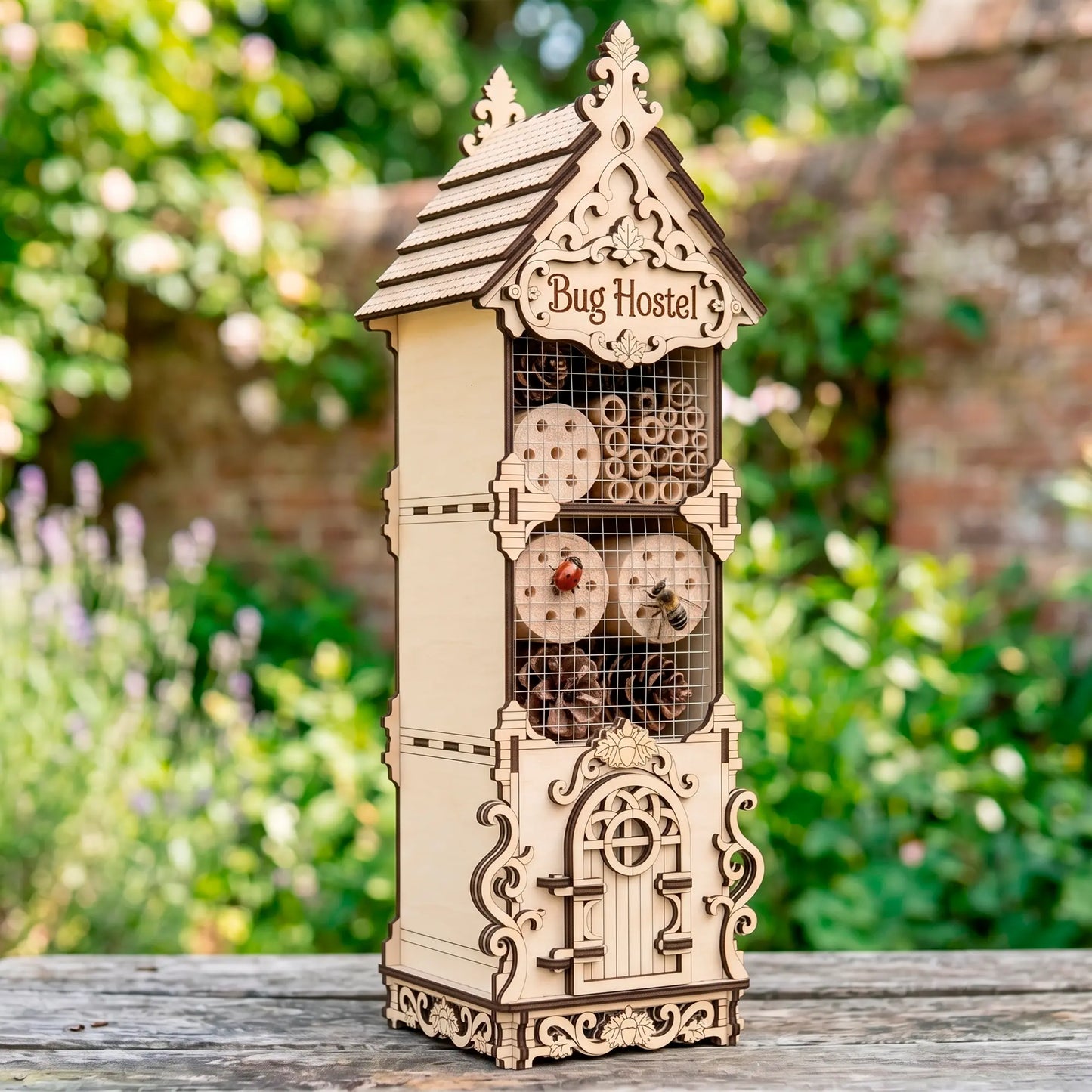Outdoor view of a laser-cut birch plywood bug hostel filled with pinecones and hollow stems, featuring a ladybug and a bee.