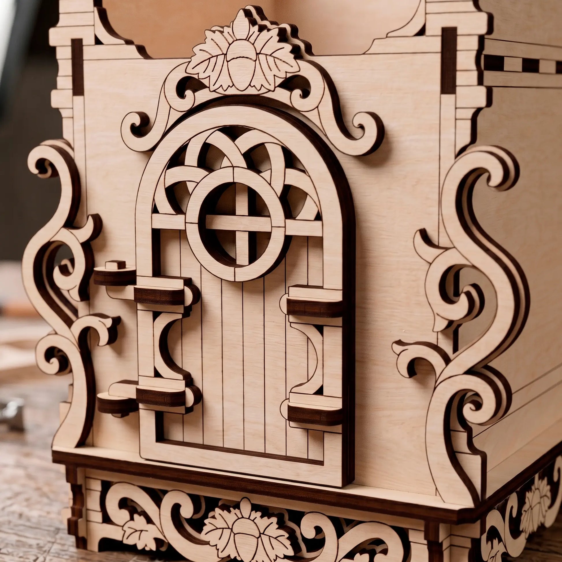 Close-up of the decorative laser-cut wooden door and intricate scrollwork on the base of the birch plywood bug hostel.