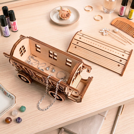 An open laser-cut plywood fairy wagon serving as a jewelry organizer filled with sparkling necklaces, rings, and earrings.