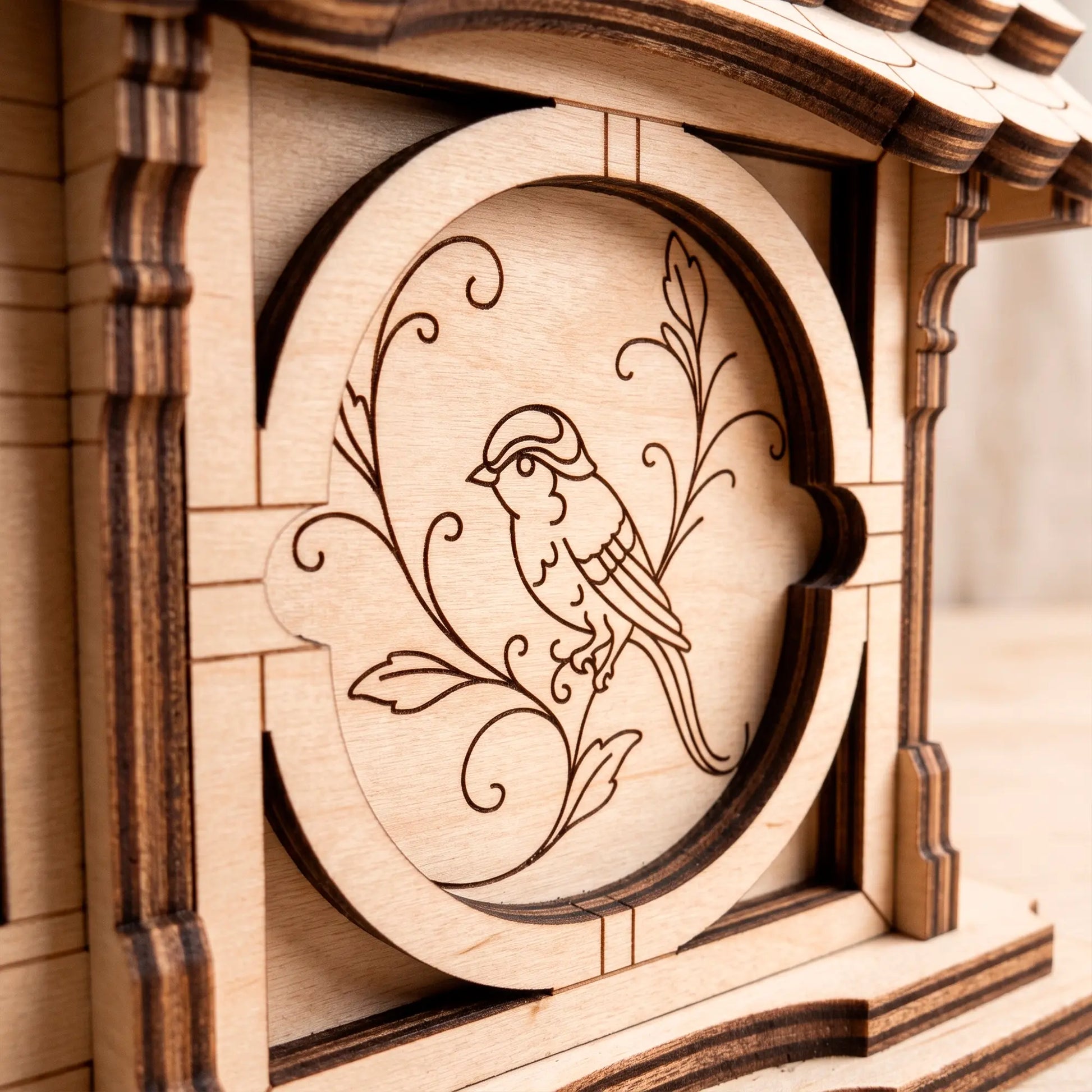 Detailed macro close-up of a laser-cut plywood side panel featuring a precisely engraved bird sitting on a floral branch.