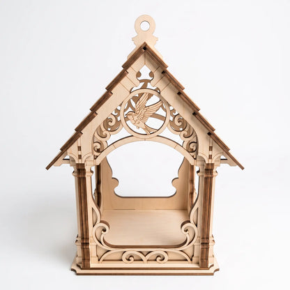 Front view of unpainted laser cut plywood bird feeder house with flying bird medallion and scrollwork on white backdrop