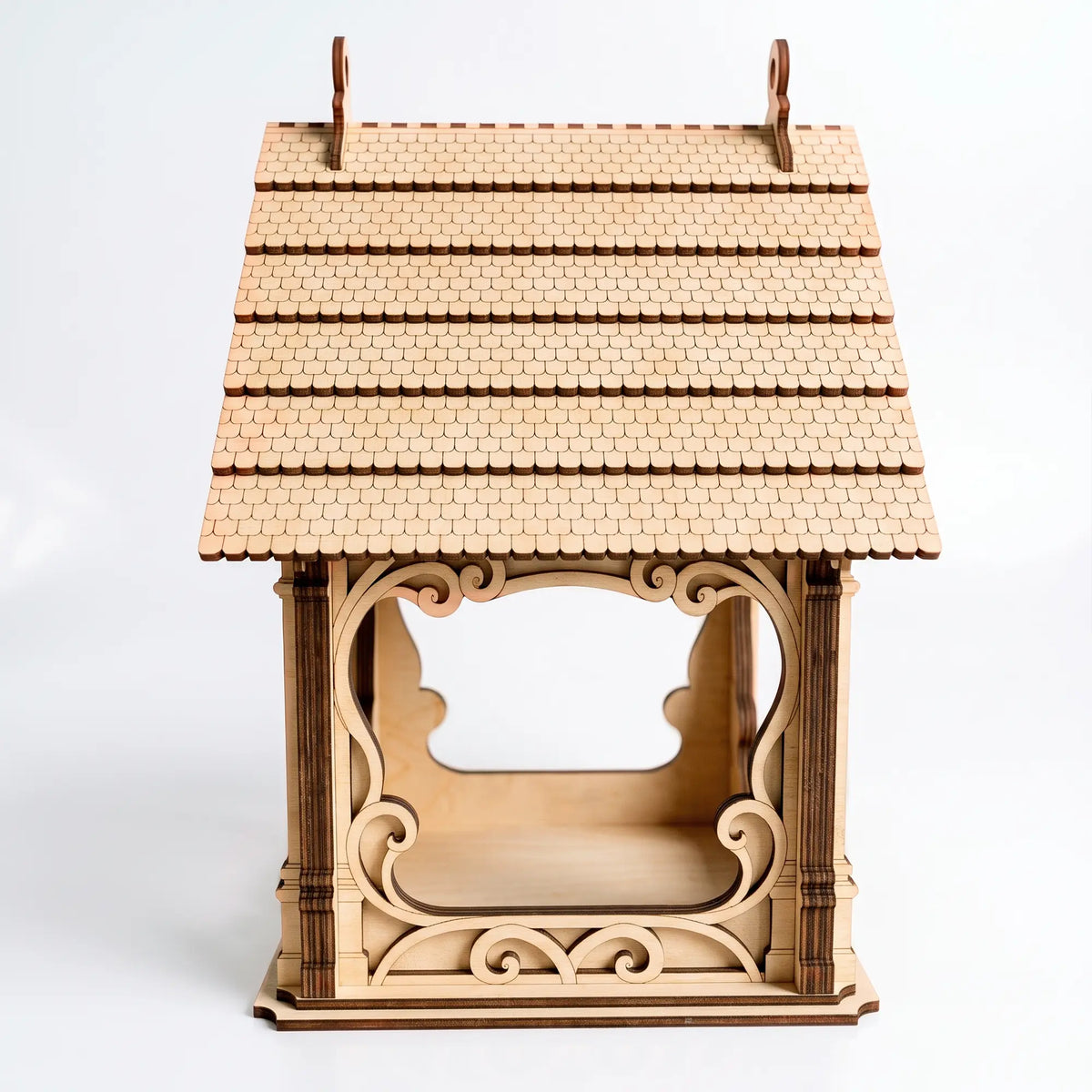 Side angle of laser cut plywood bird feeder showcasing delicate wooden shingles on the roof over white background.