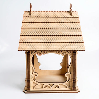 Side angle of laser cut plywood bird feeder showcasing delicate wooden shingles on the roof over white background.