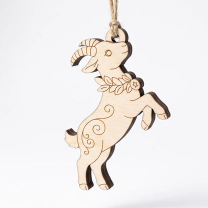 Laser cut plywood jumping goat ornament hanging on twine string with engraved floral collar against plain white background.