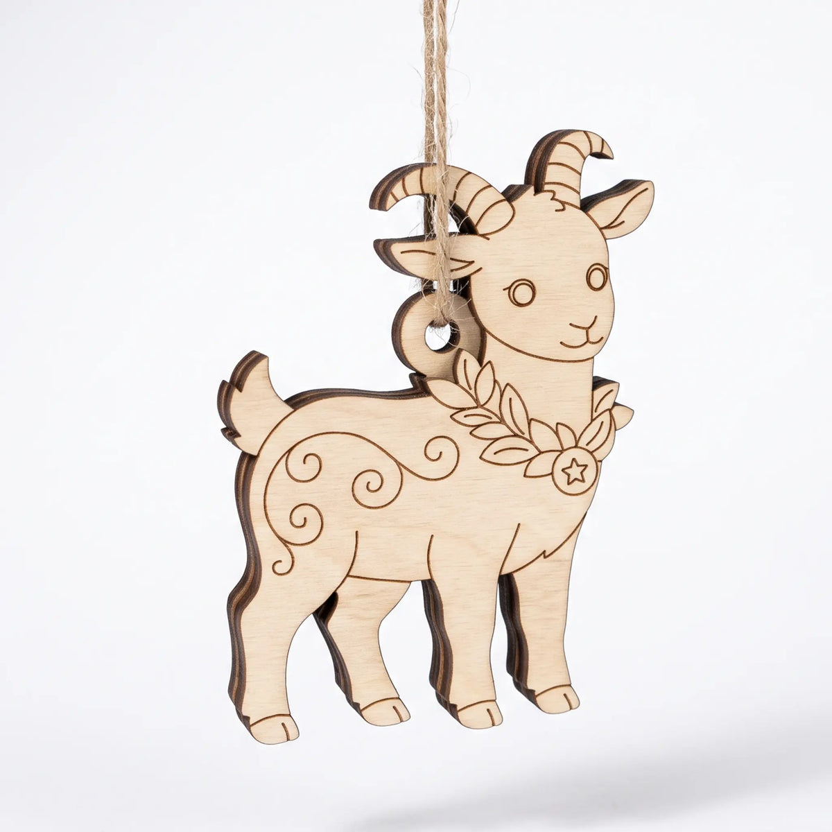 Front three-quarter view of hanging laser cut plywood goat ornament with curved horns and festive star wreath collar.
