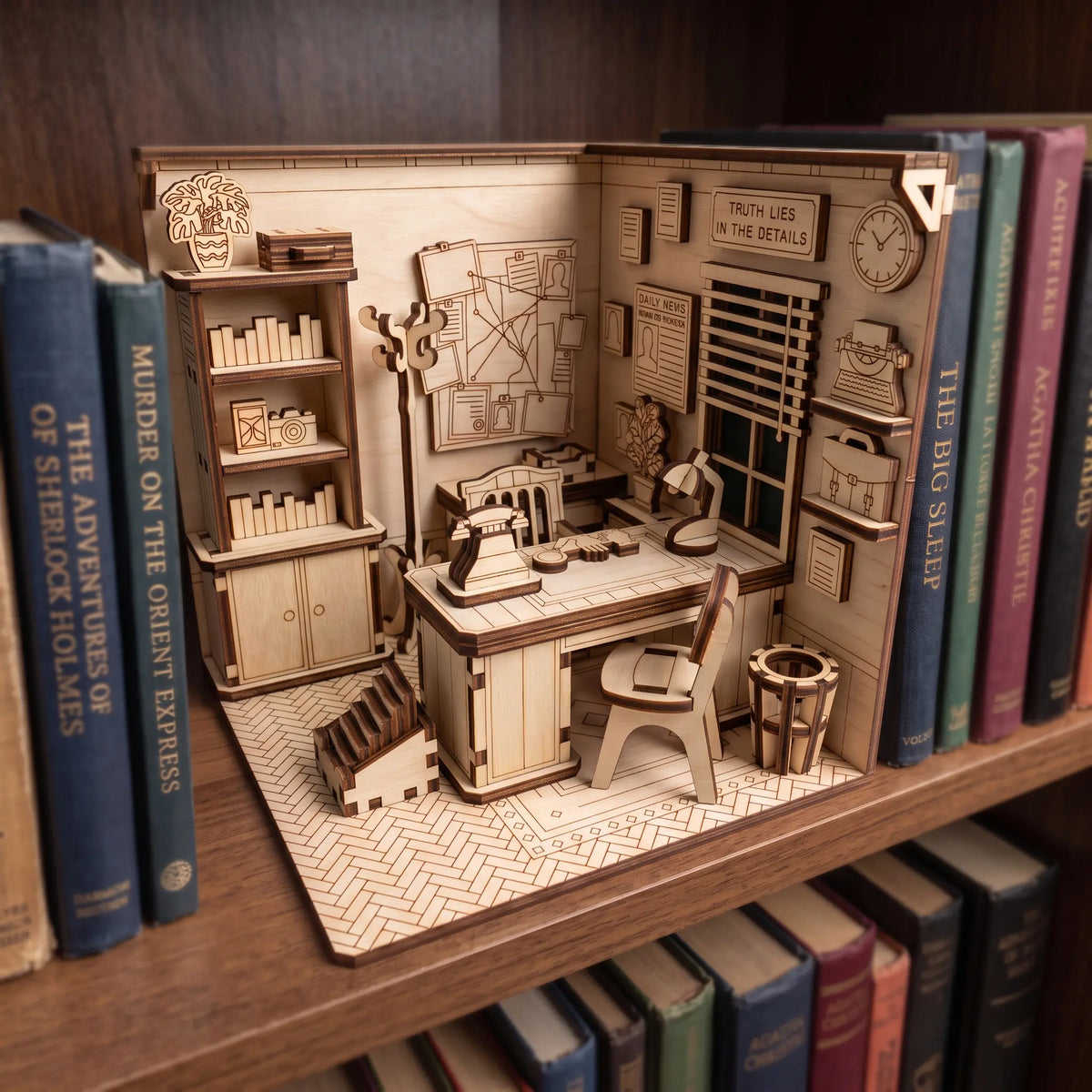 Laser cut plywood detective office book nook diorama placed on bookshelf between Sherlock Holmes and Agatha Christie novels.