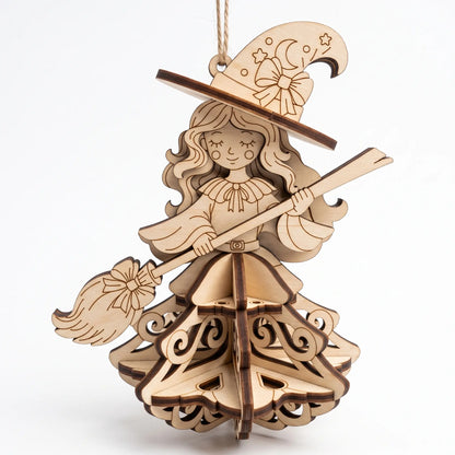 Front view of a hanging laser cut plywood witch ornament with broom, pointed hat, and slotted 3D skirt on white backdrop.