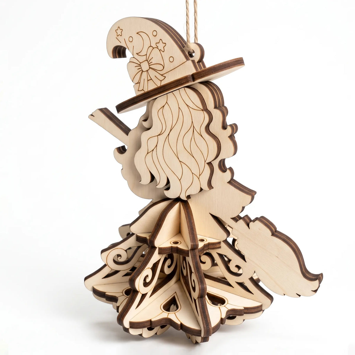 Back angle view of laser cut plywood witch hanging ornament showing wavy hair, broom, and 3D tiered skirt on white backdrop.
