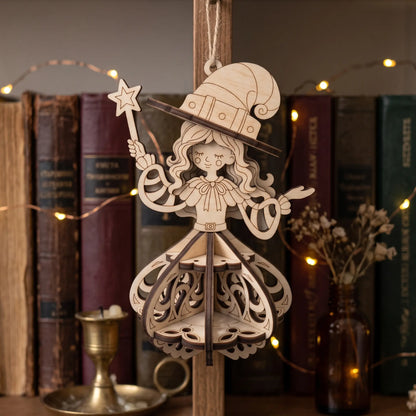 Laser cut plywood witch ornament hanging on wooden stand in front of vintage books, brass candle, and fairy lights.