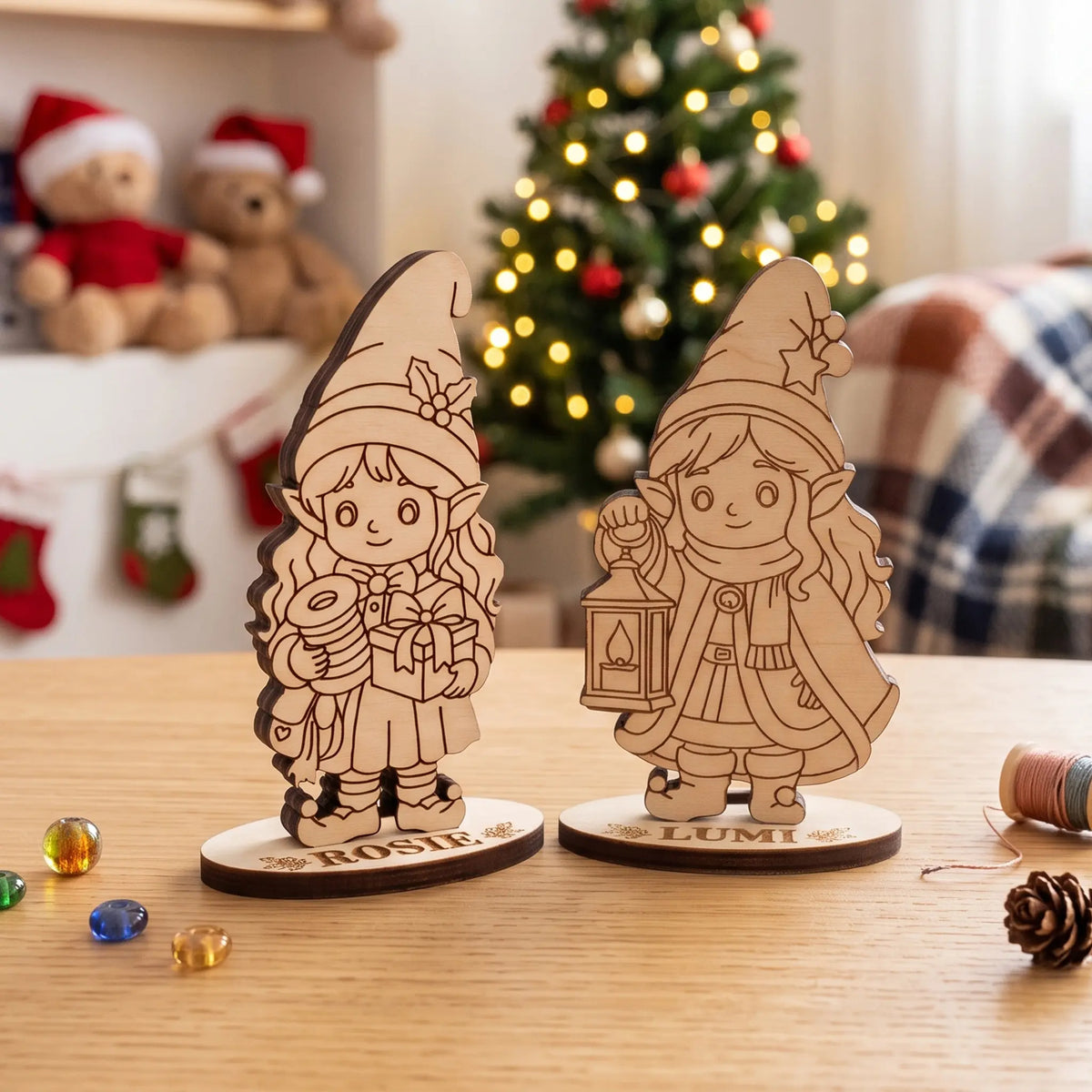 Two unpainted laser cut plywood standing elves Rosie and Lumi on wooden table with holiday tree background.
