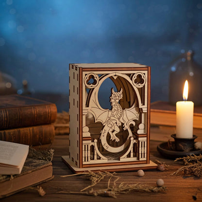 Wooden lantern with dragon laser cut design on a table with books and a candle.
