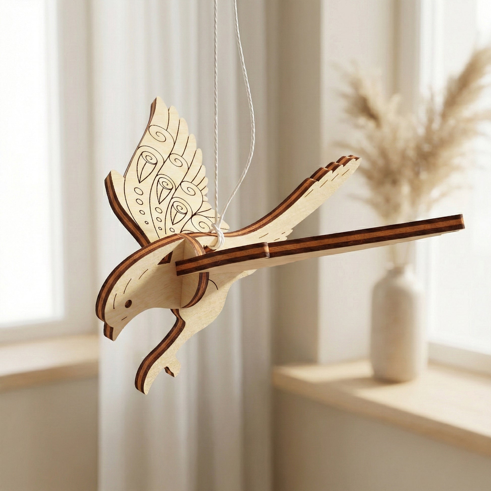 Wooden laser cut bird ornament hanging against a light background
