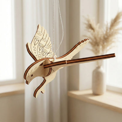 Wooden laser cut bird ornament hanging against a light background