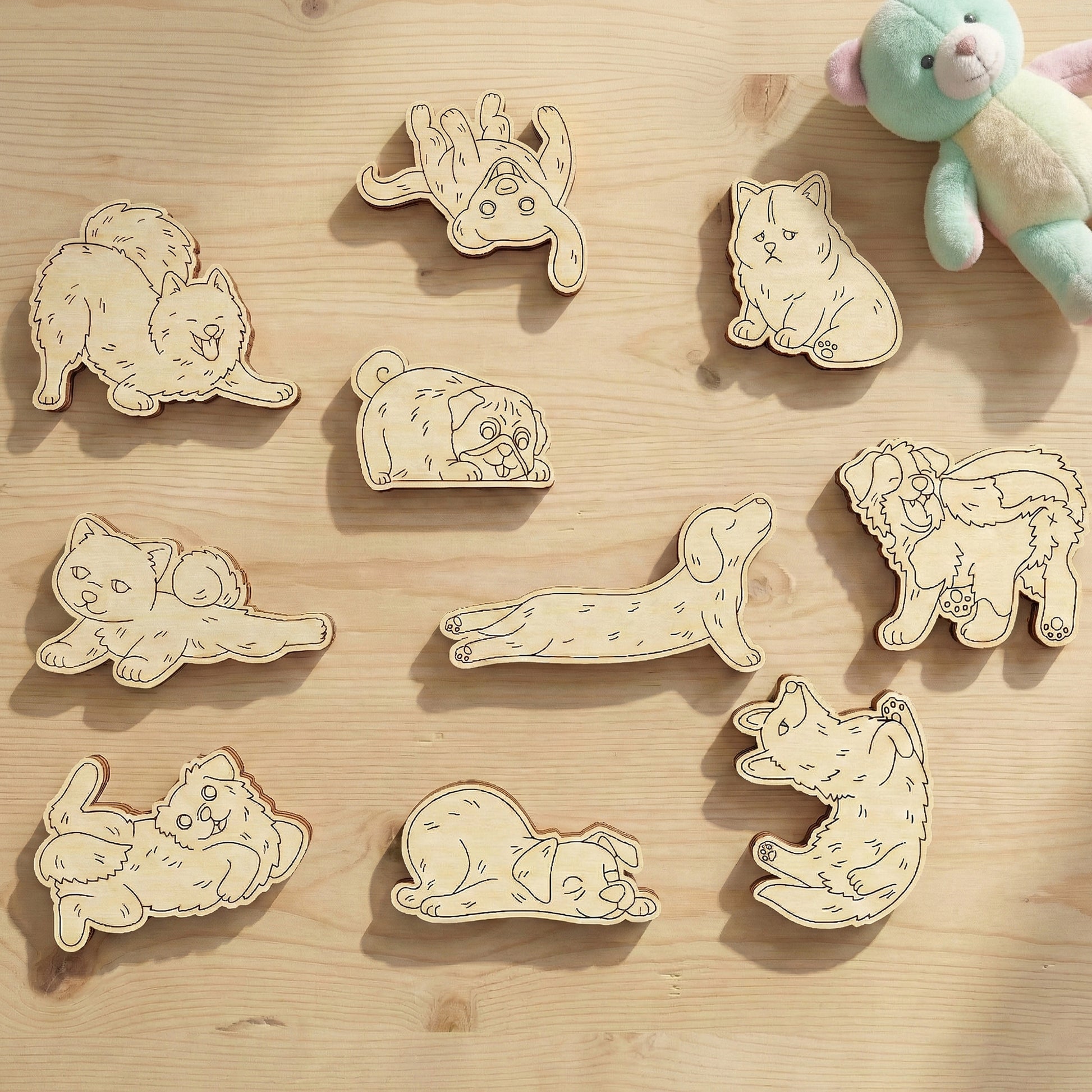 Wooden dog laser cut shapes on a wooden surface with a plush toy in the corner.