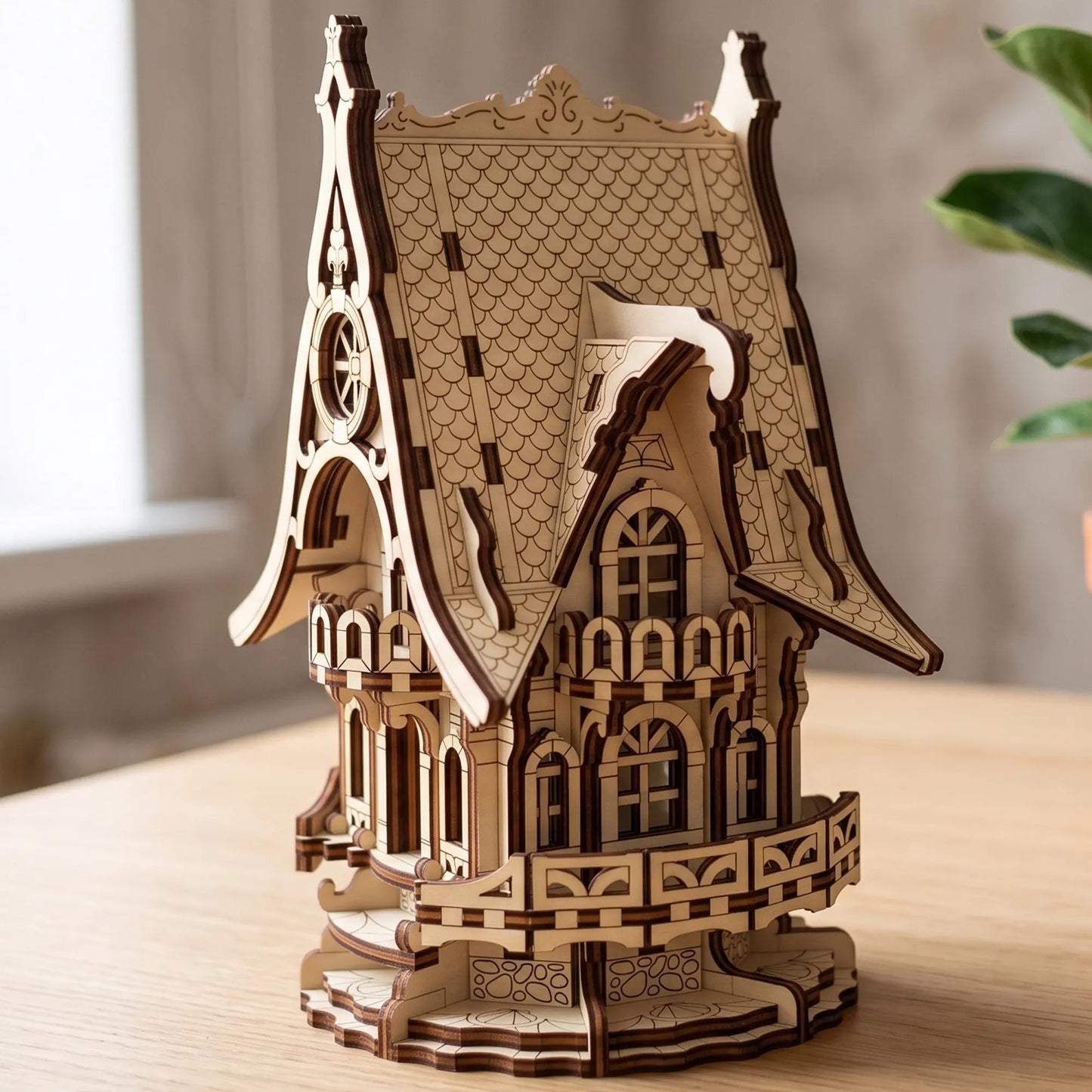 A 3D wooden model of a Victorian-style house with intricate laser-cut details, displayed on a light wooden table 