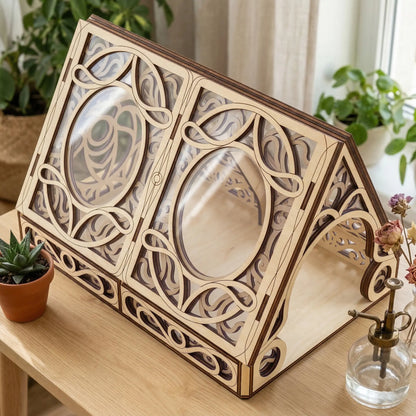 Wooden laser cut greenhouse with intricate designs on a wooden surface with plants in the background