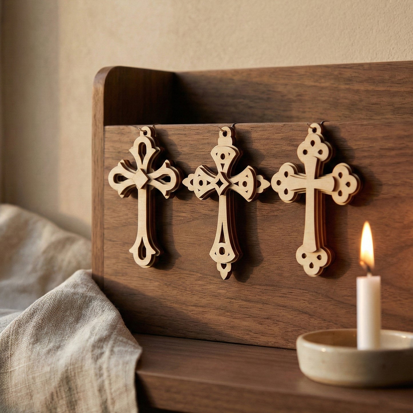 Wooden laser cut cross decorations on a wooden board with a lit candle in the background.