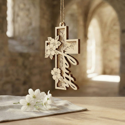 Decorative wooden laser cut cross with floral designs hanging on a stone wall.