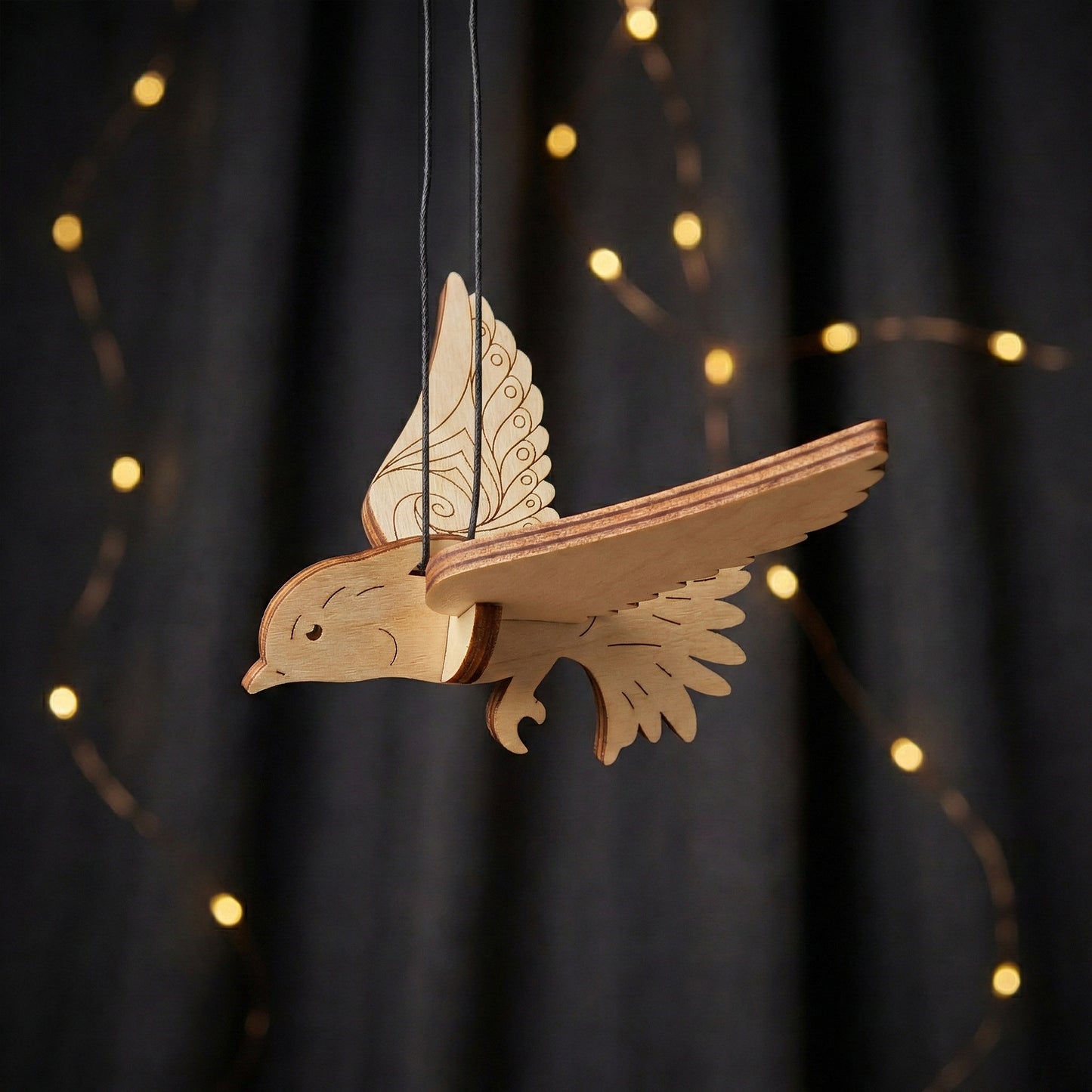 Wooden laser cut  dove ornament hanging against a dark background with string lights.