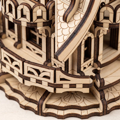 Close-up of a laser-cut wooden architectural model or puzzle piece showing detailed construction with light natural wood and dark burned edges.
