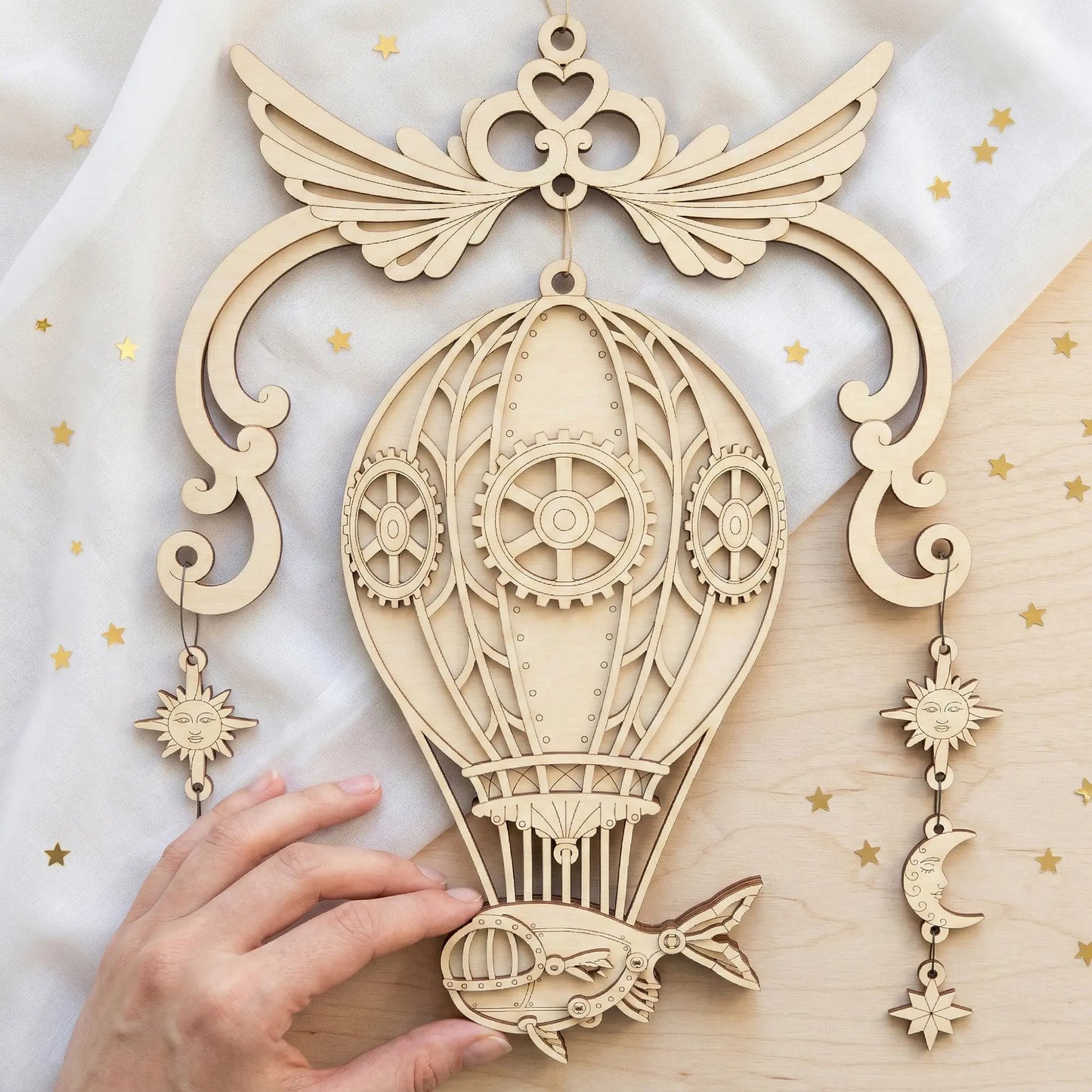 Laser cut decorative hot air balloon with gears and celestial elements on a light background
