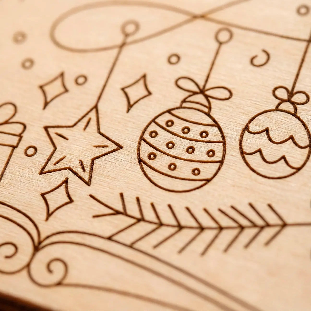 Wooden surface with engraved Christmas decorations including stars and baubles.
