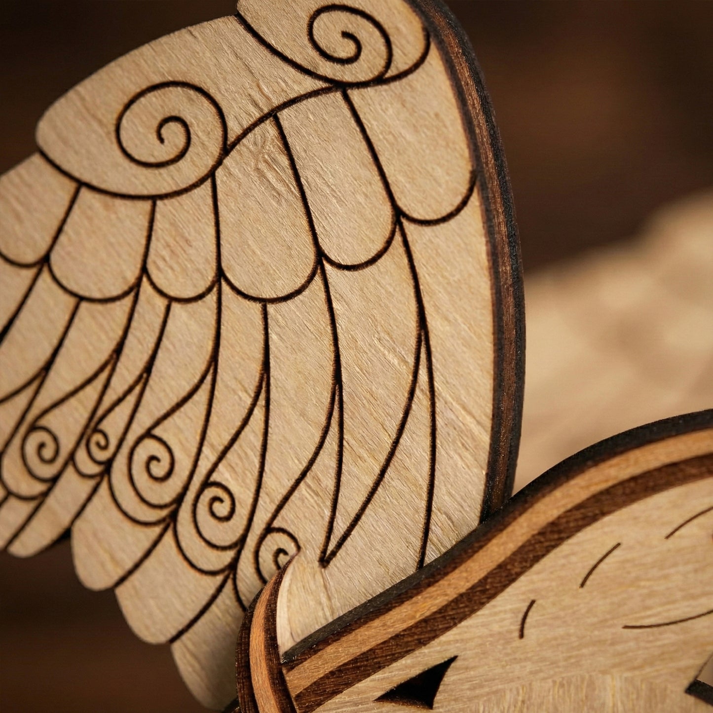 Close-up of wooden laser cut bird wings with intricate detailing on a blurred background