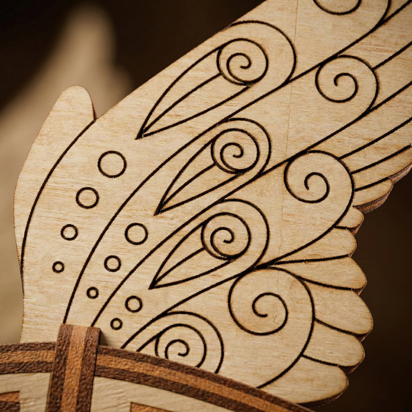 Wooden laser cut bird wing with intricate carvings on a dark background