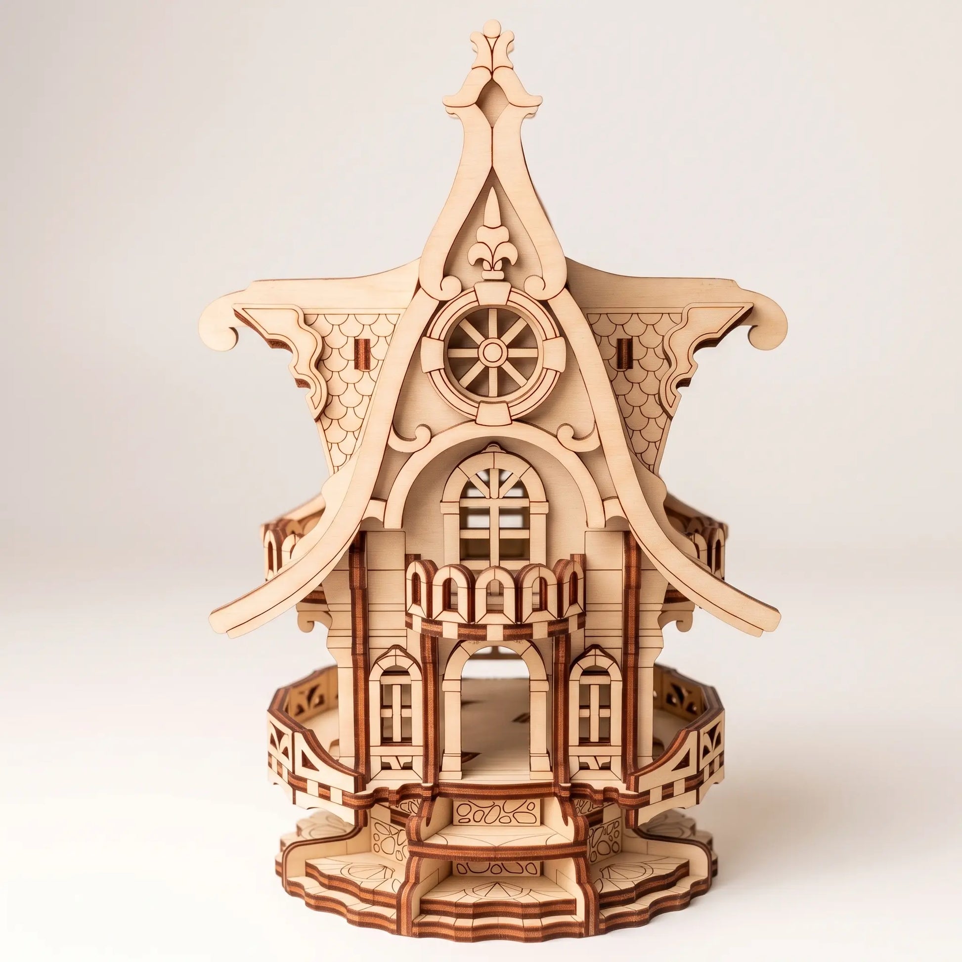A 3D wooden model of an ornate house, constructed from laser-cut light brown wood pieces, shown on a neutral light gray background.