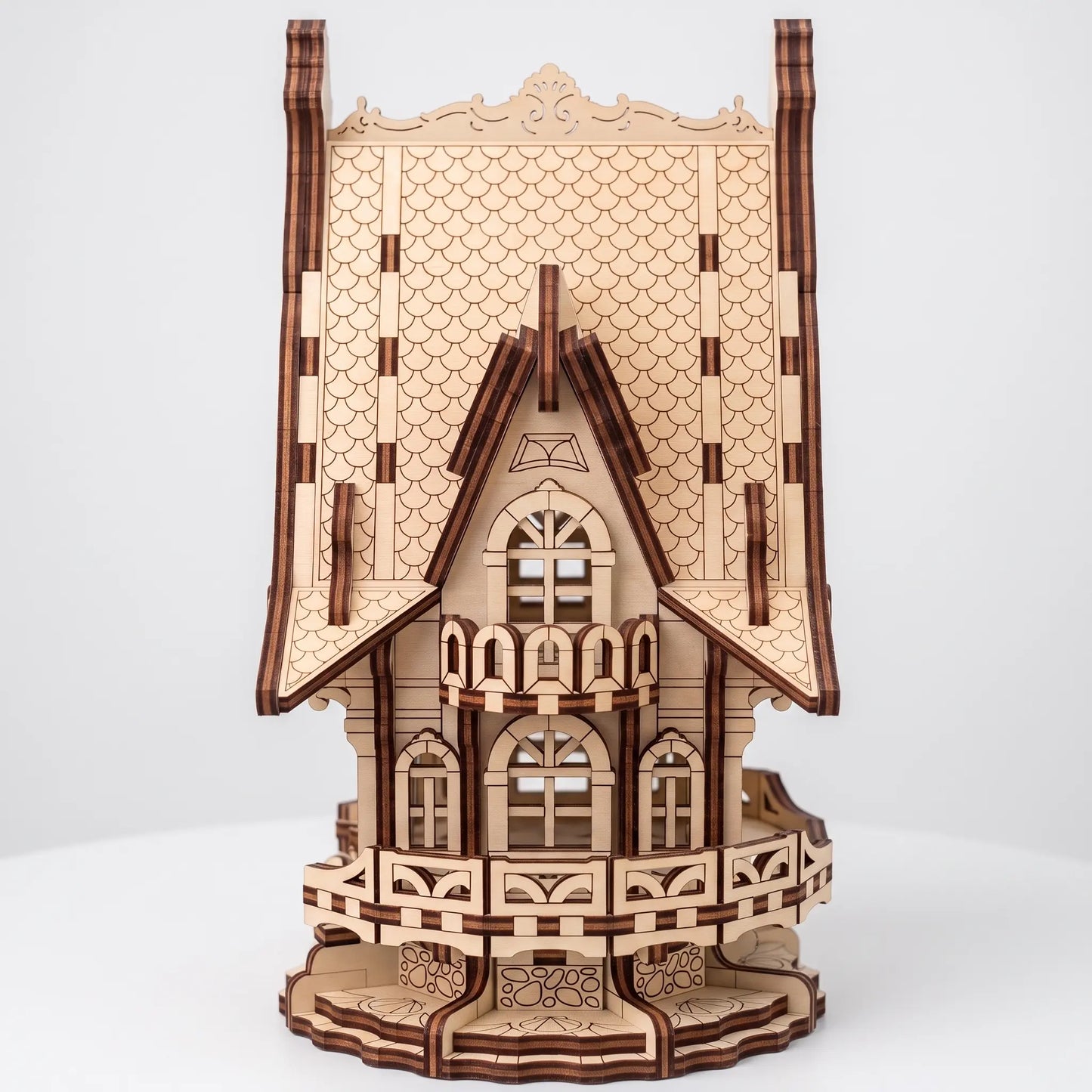 A 3D wooden model of an ornate Victorian-style house, constructed from laser-cut light brown wood with darker brown engraved details, shown on a light gray background.