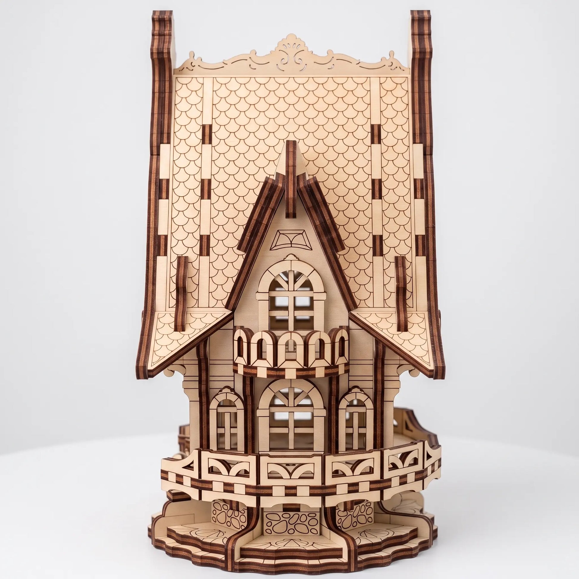 A 3D wooden model of an ornate Victorian-style house, constructed from laser-cut light brown wood with darker brown engraved details, shown on a light gray background.