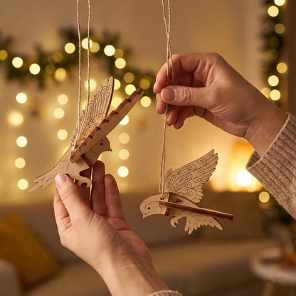 Wooden laser cut bird ornaments being held against a warm, blurred indoor background with lights.
