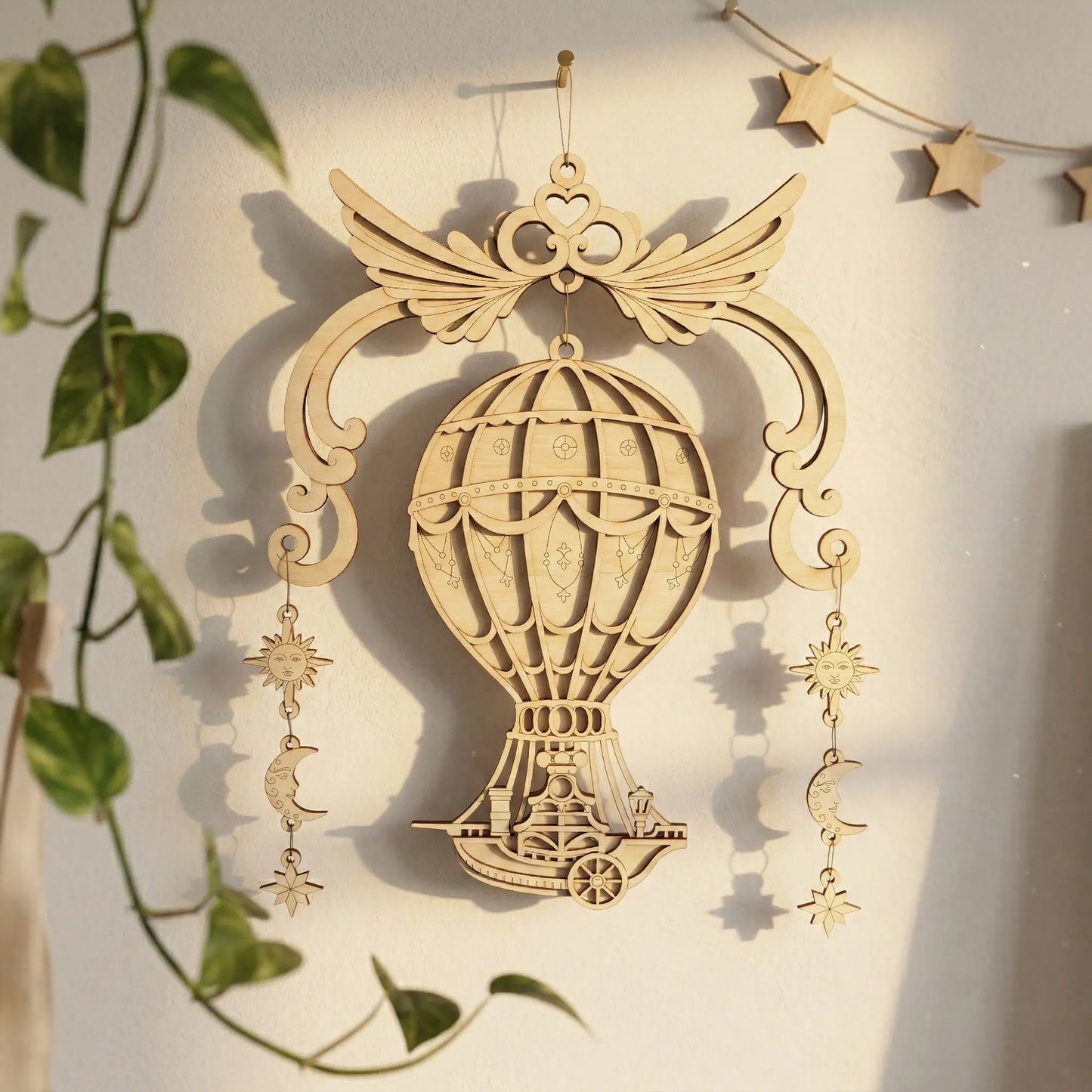 Laser cut hot air balloon ornament with star and moon charms on a light background