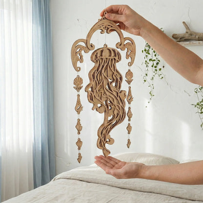 Wooden laser cut jellyfish wall hanging held by a person against a white wall with plants.