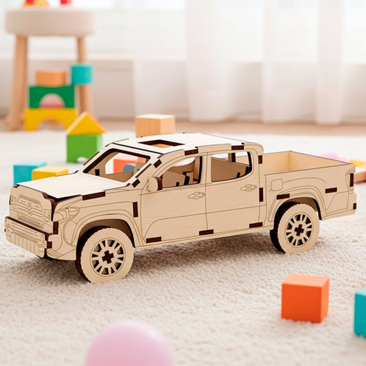 Laser cut plywood wooden 3D model kit of a modern pickup truck with four doors and an open bed, displayed on a soft white rug surrounded by colorful toy blocks in a bright indoor playroom setting