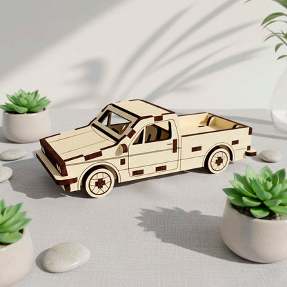 Side profile of a laser cut wooden plywood pickup truck 3D model. The wooden craft features detailed wheel engravings and an open cargo bed, styled with potted succulent plants and pebbles in a bright, minimalist interior setting.