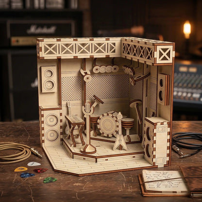 Wooden laser cut model of a music studio with speakers and equipment on a wooden surface.