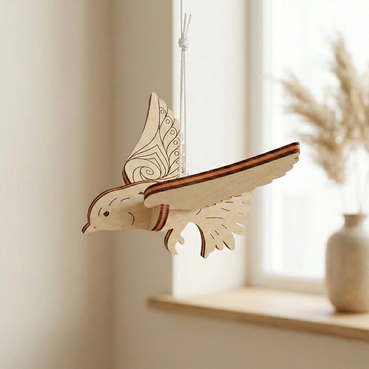 Wooden laser cut bird ornament hanging on a shelf with a neutral background