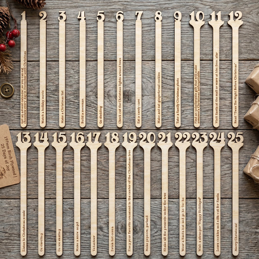 Laser cut plywood Christmas advent calendar sticks in a glass cup on a wooden table, styled with festive pine branches.