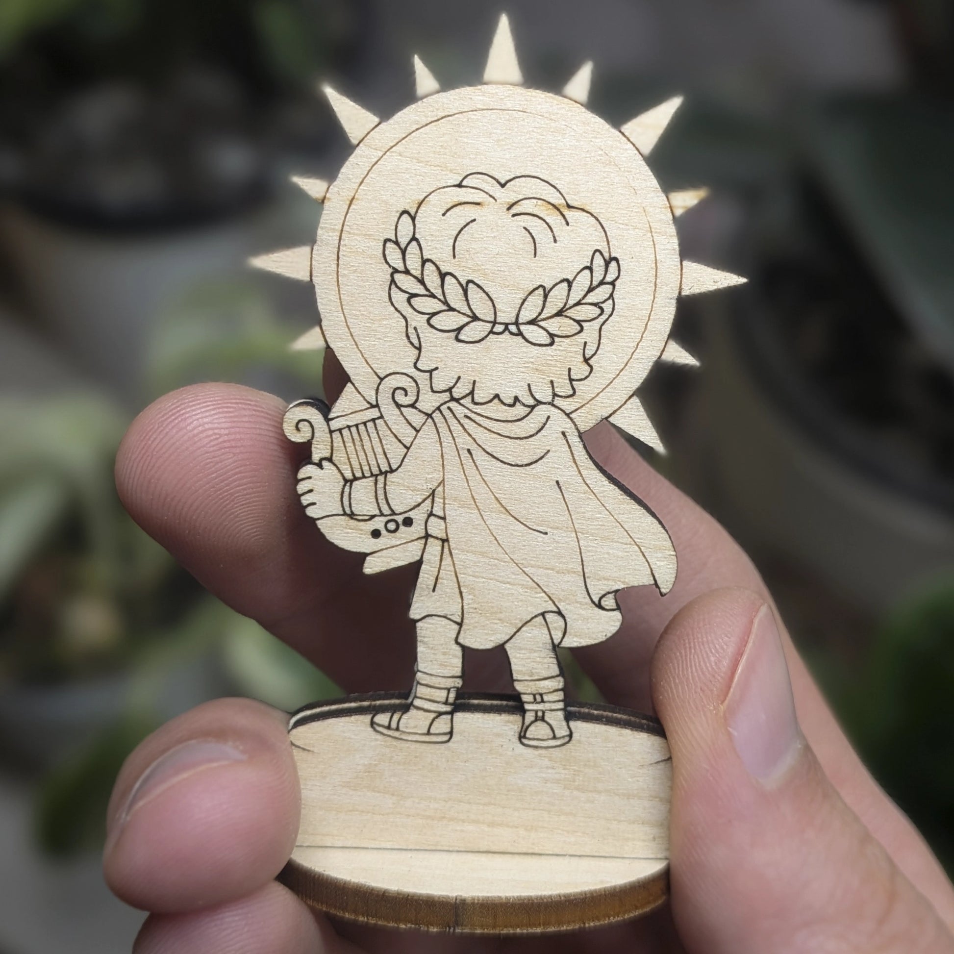 Back view of a laser cut plywood Apollo held in hand. Highlights the dark burnt wood edges and natural plywood grain texture