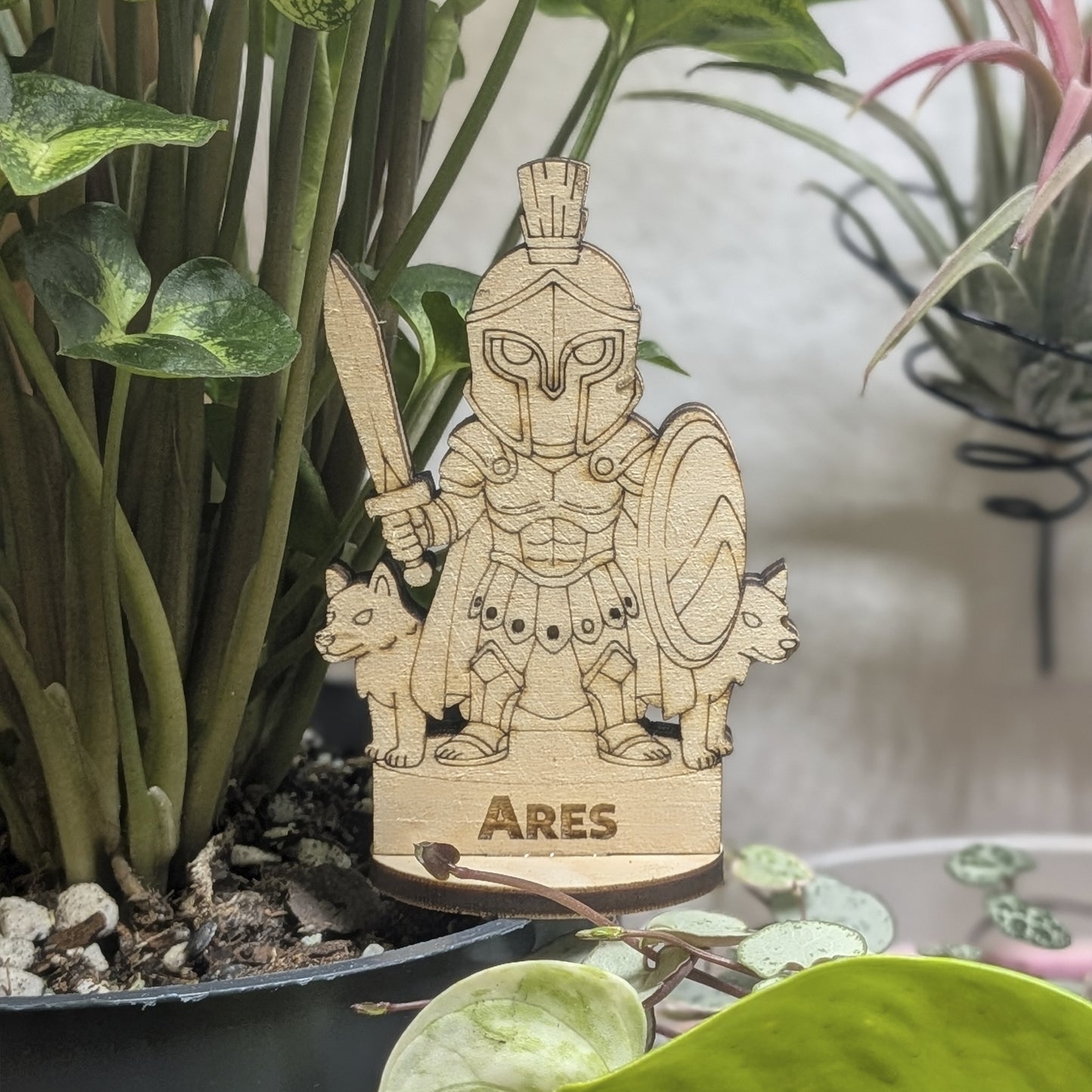 Laser cut plywood Ares figurine in a plant pot. Features a plumed helmet, spear, and round Greek shield on wood base