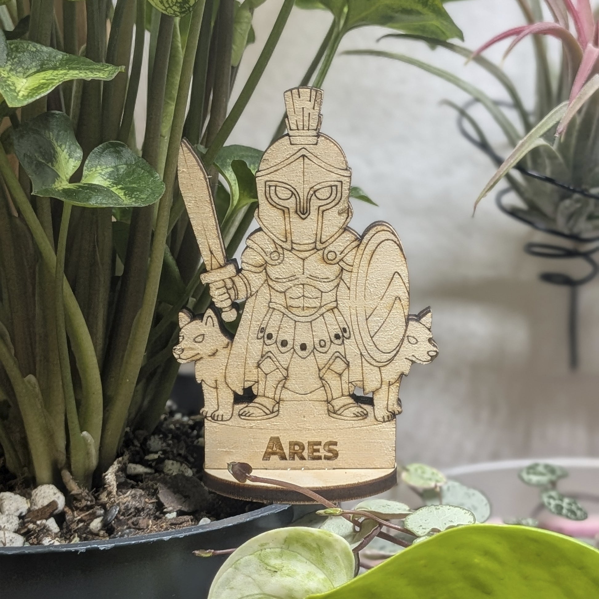 Laser cut plywood Ares figurine in a plant pot. Features a plumed helmet, spear, and round Greek shield on wood base