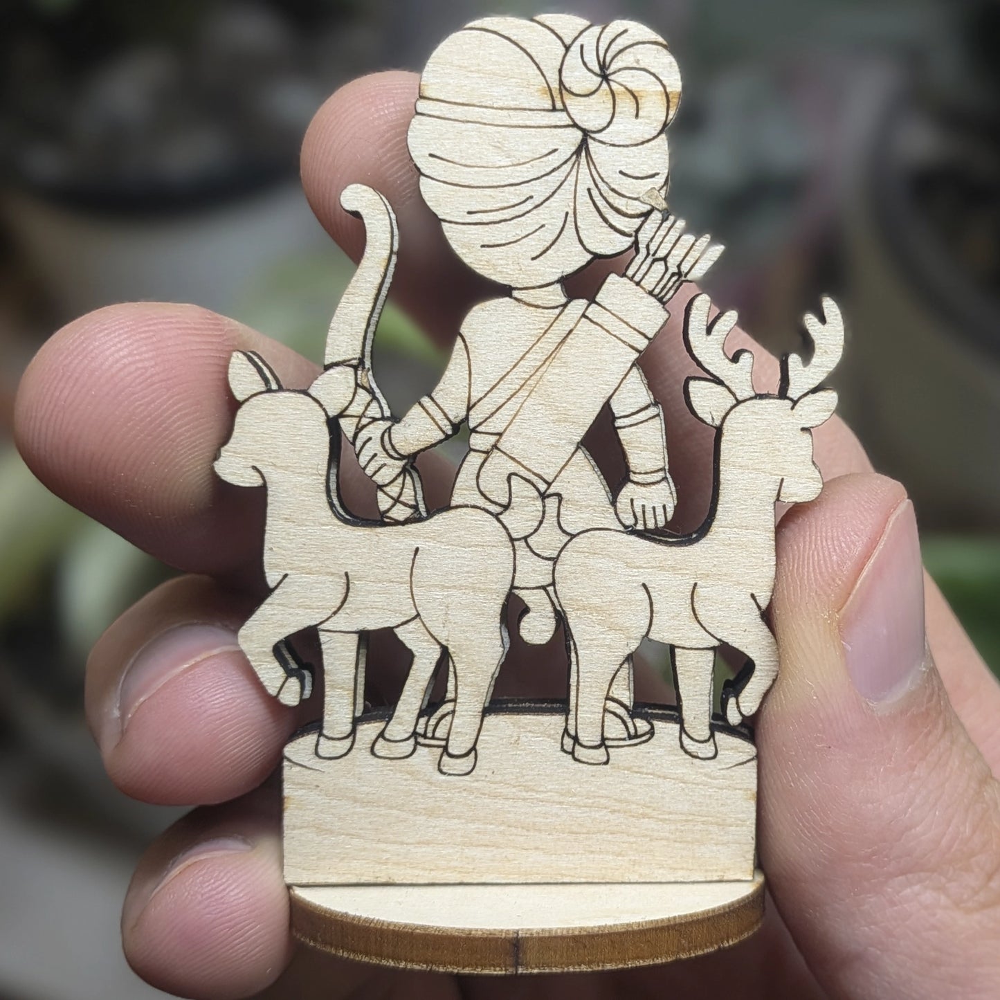 Back view of a laser cut plywood Artemis held in hand. Highlights the dark burnt wood edges and natural plywood grain texture