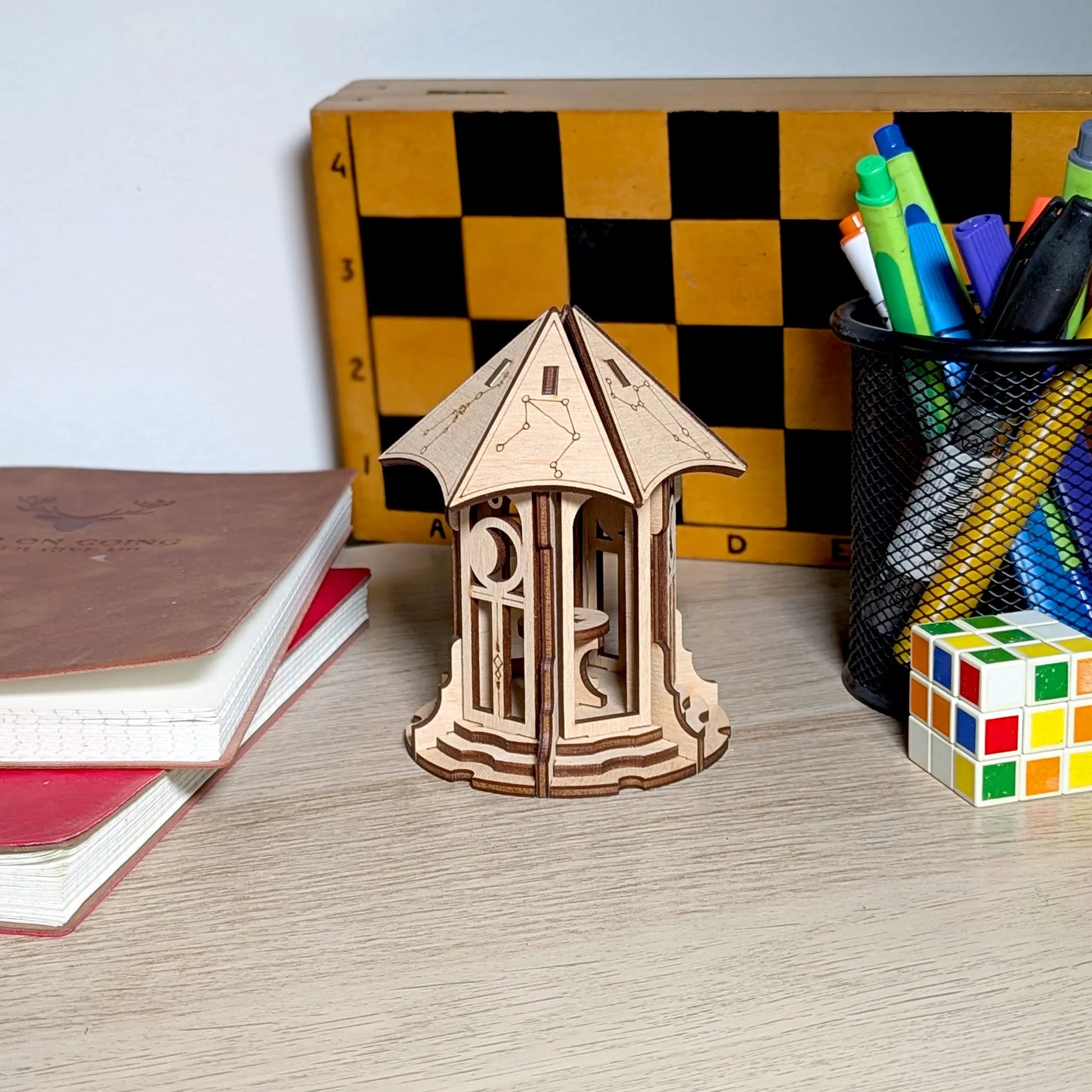 An aesthetic lifestyle shot of a miniature astronomical gazebo made from laser cut plywood, styled beautifully on a table.