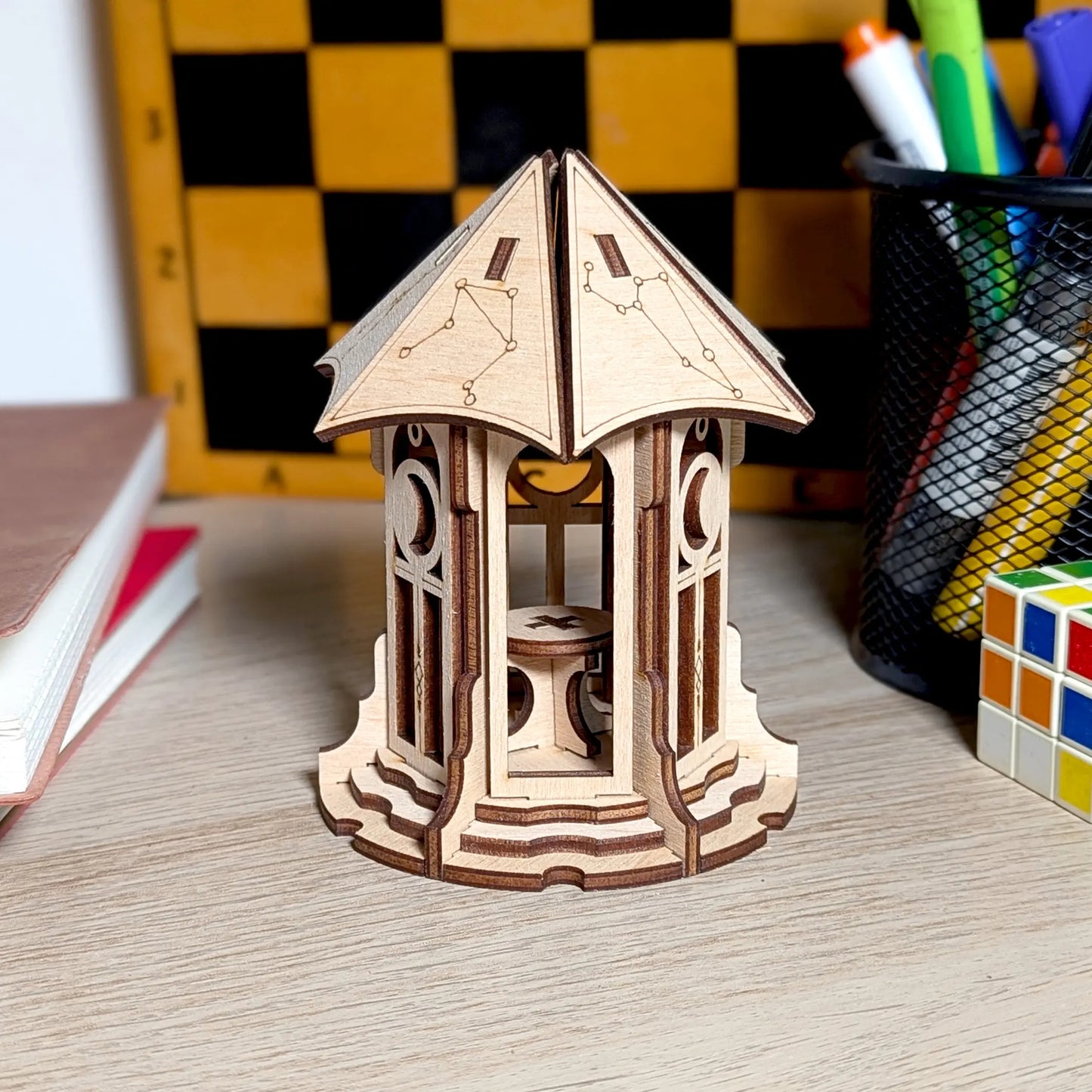 Three-quarter view of a rustic miniature astronomical gazebo model with engraved details, crafted from laser cut plywood.